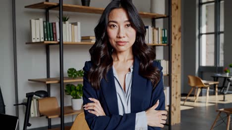 professional businesswoman standing confidently in contemporary office, arms crossed, embodying leadership and success with poised, assertive demeanor and elegant corporate presence