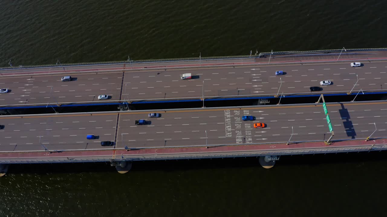 교통량이 많은 강을 건너는 다리 위를 비행하는 드론 샷
