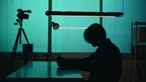 medium silhouette video of a suspect offender perpetrator or prisoner sitting in the interrogation medium silhouette video of a suspect offender perpetrator or prisoner sitting in the interrogation room he is studying the evidence on the table true crime documentary creative content
