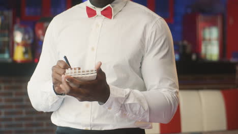 waiter taking an order in a retro restaurant and smiling