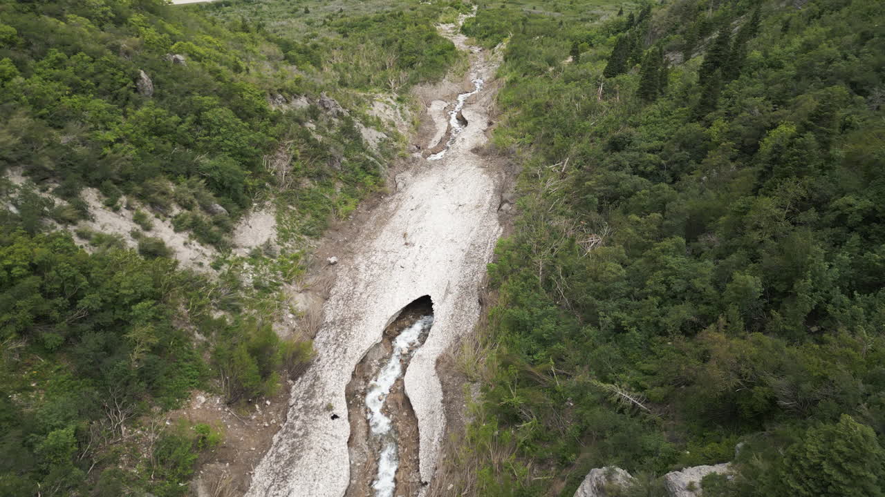 vista aérea mirando hacia abajo sobre el lecho de un río glacial escarpado con una abertura de roca a cuevas de hielo en provo, utah