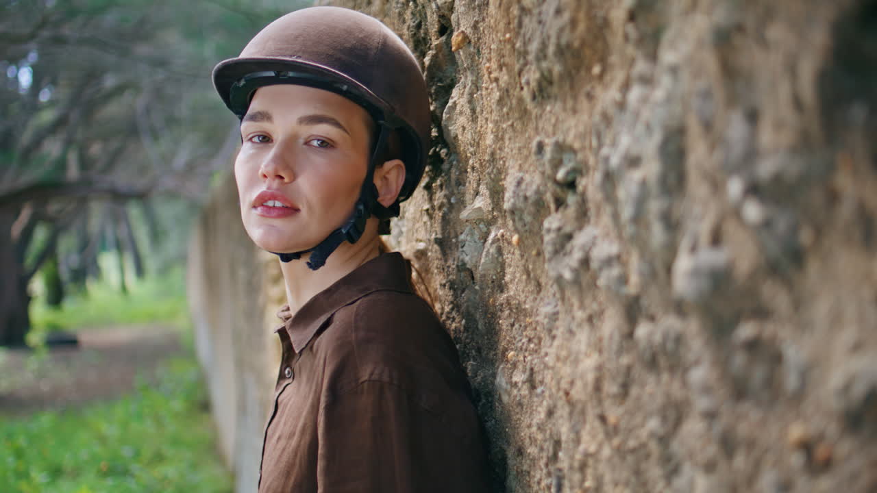 Flirty equestrienne posing camera spikelet hands in horse riding arena portrait