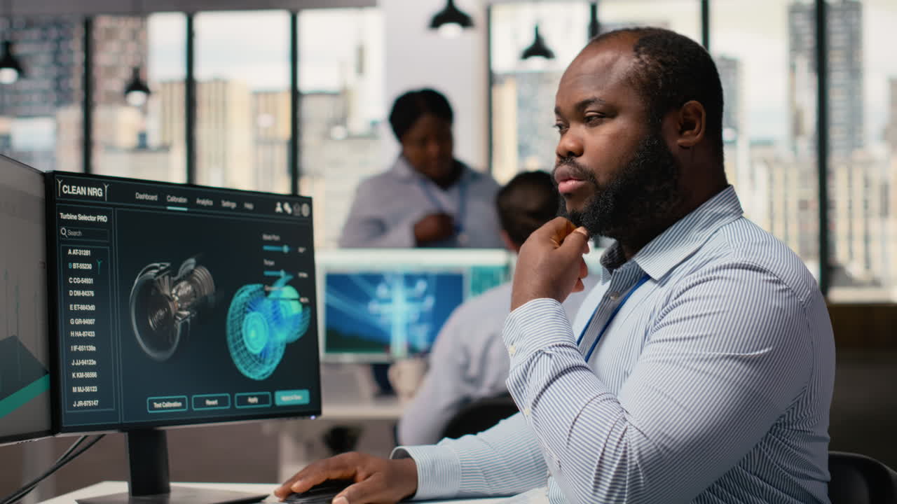 Renewable Energy Engineer In Office Upgrades Windmill Farm Infrastructure