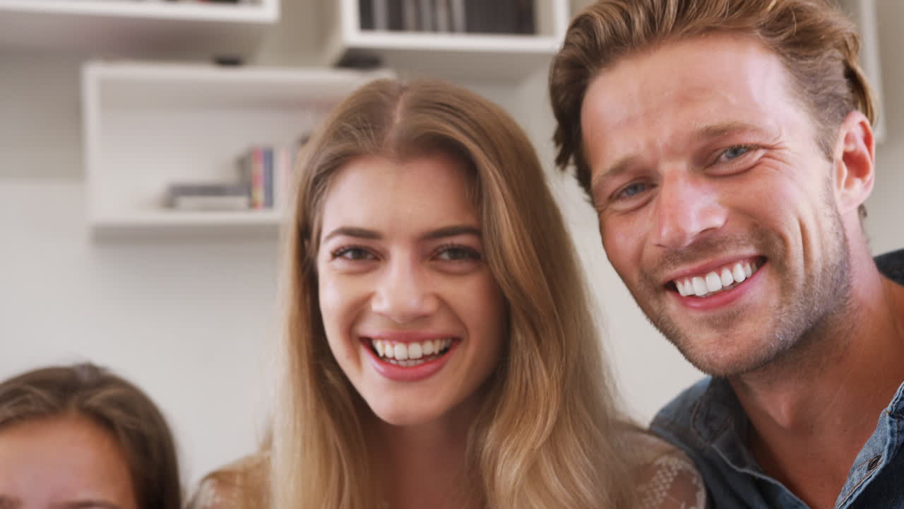 retrato de una familia sonriente sentada en el sofá en casa juntos