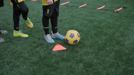 a children's football team trains at the stadium under the guidance of a coach. kids in sports uniforms practice ball exercises, improve technique, and develop teamwork on the green field