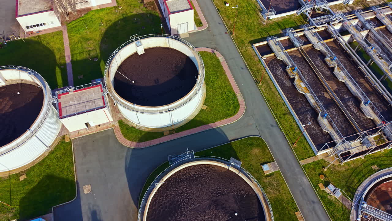 Water treatment facility shows multiple tanks and processing equipment in operation in a modern urban area during daylight hours