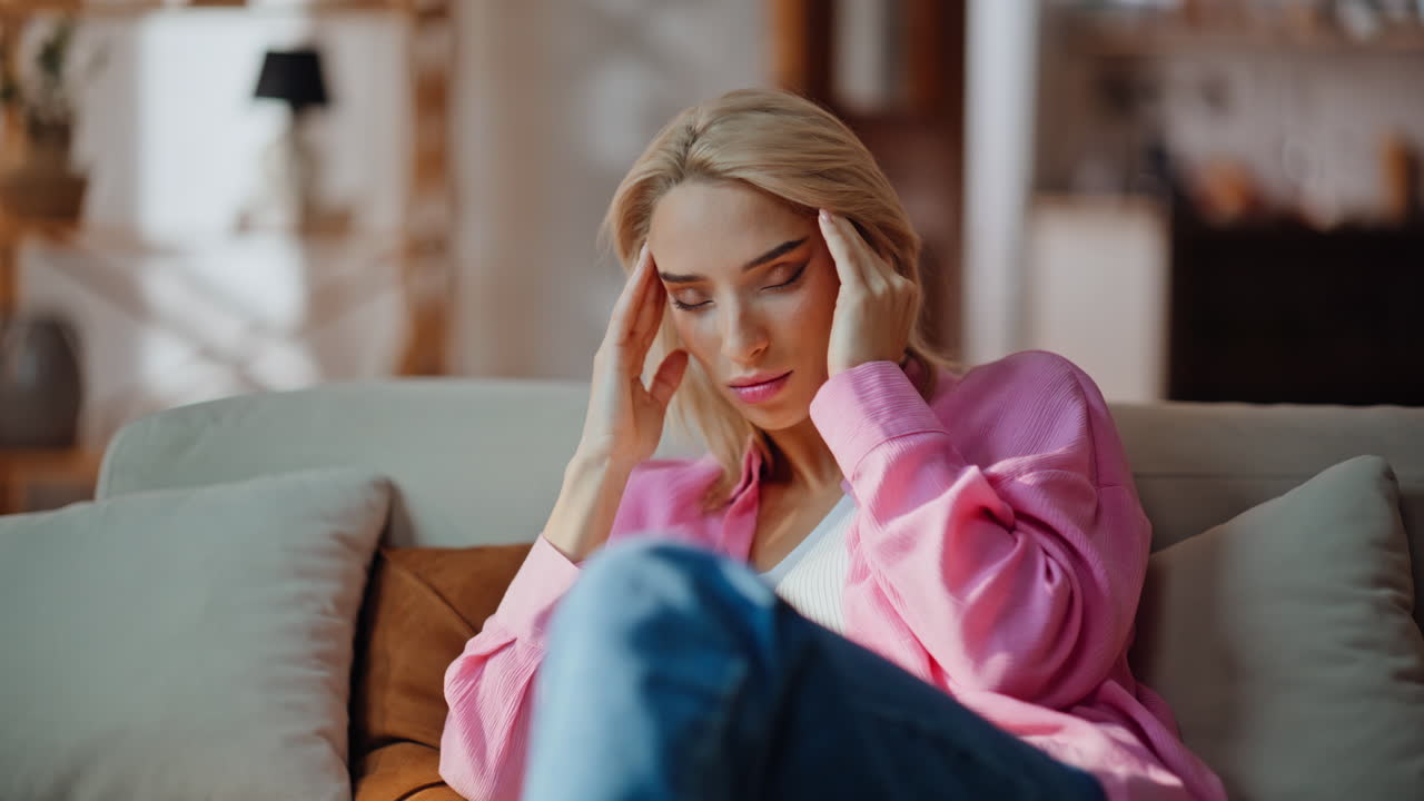 Headache woman finish call mobile phone at home sofa closeup. Girl rubbing head