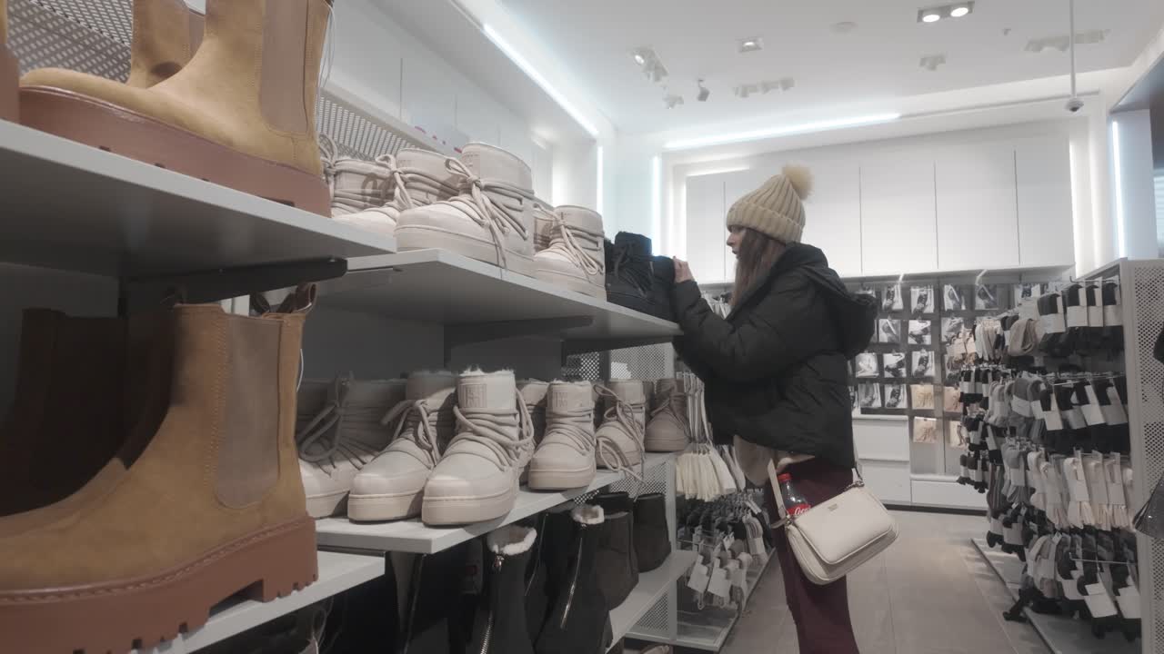 Esposizione su scaffale, ragazza che curiosa, calzature alla moda ed eleganti, saldi di stivali