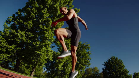 male athlete training on a track under a sunny sky