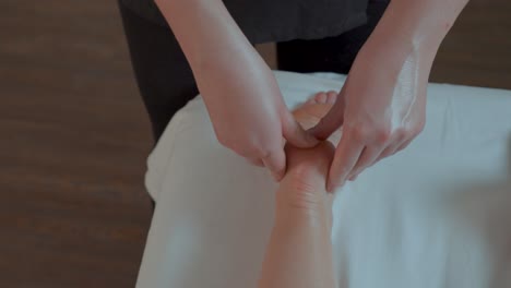 slow revealing shot of a masseuse massaging a client feet and ankles