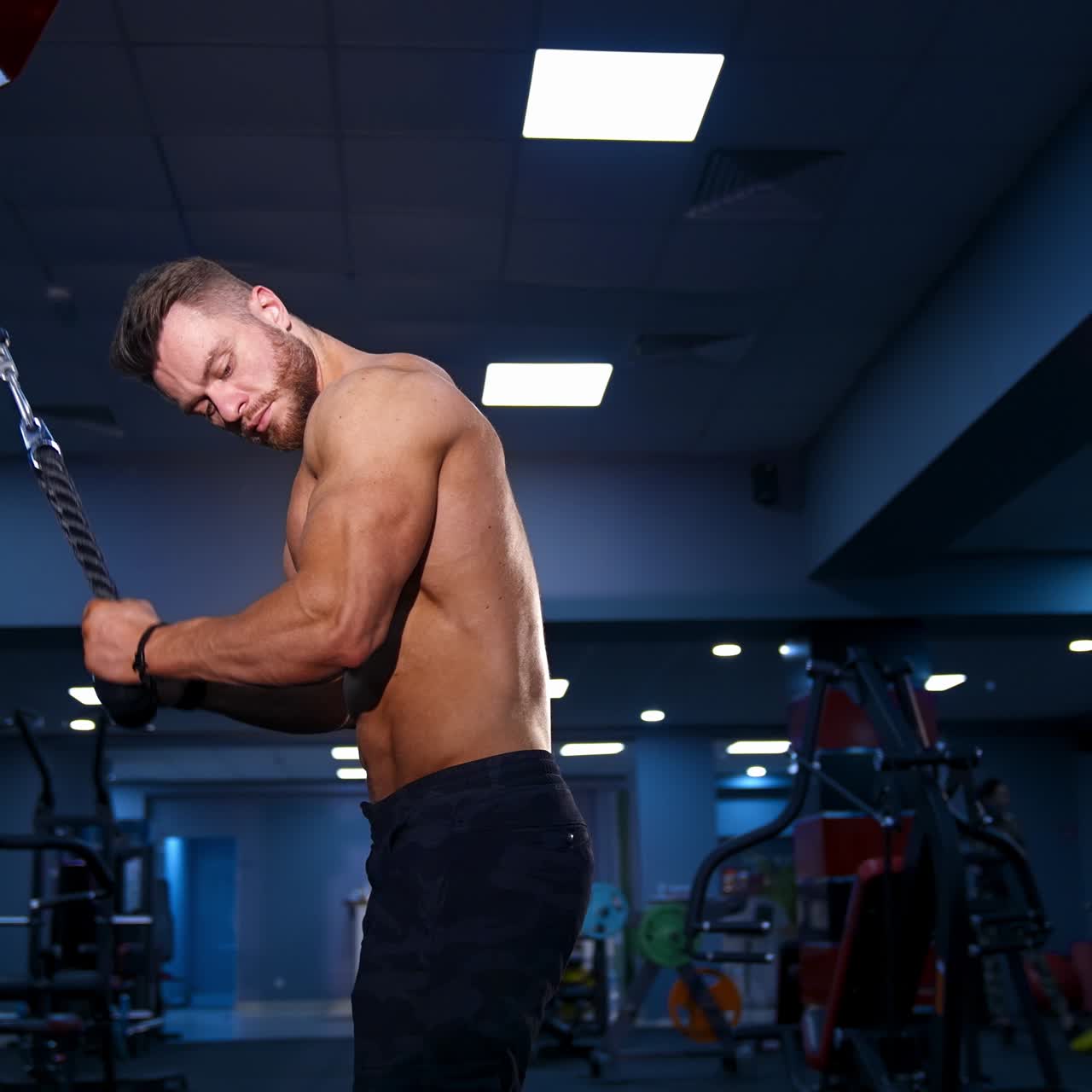 Fitness man pumping up arm muscles. Bodybuilder doing arms exercises with naked torso in gym. Handsome power athletic man at training. Workout indoors.