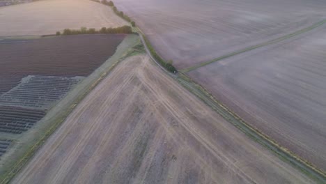 volando lentamente a través de campos cosechados para revelar balas de heno