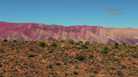 Drone-footage-emerging-from-behind-a-mountain,-revealing-the-breathtaking-landscapes-of-the-Hornocal