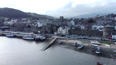 Picturesque-Conwy-castle-and-harbour-fishing-town-boats-on-coastal-waterfront-aerial-dolly-left