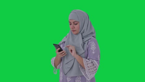 mujer musulmana seria usando pantalla verde del teléfono