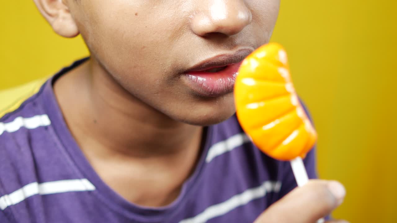 Boy eating a yellow lollipop