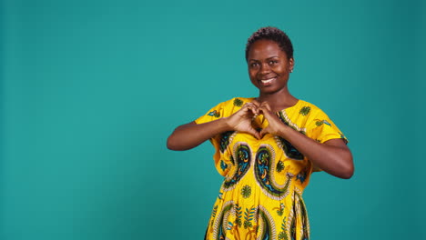 sweet gorgeous girl showing a heart shaped sign with her hands in studio