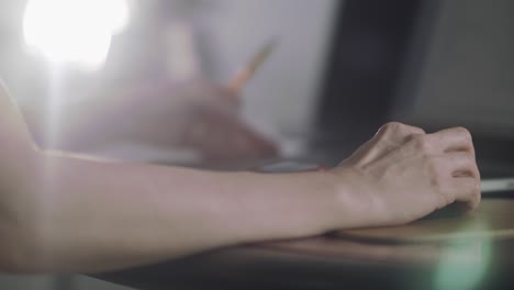 mujer trabajando en su computadora portátil, desplazándose con su mouse, sosteniendo un lápiz