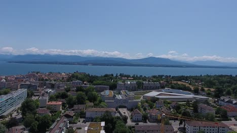 drone view reveals picturesque cityscape by calm lake under clear blue sky, capturing serene beauty of switzerland's landscape during daytime