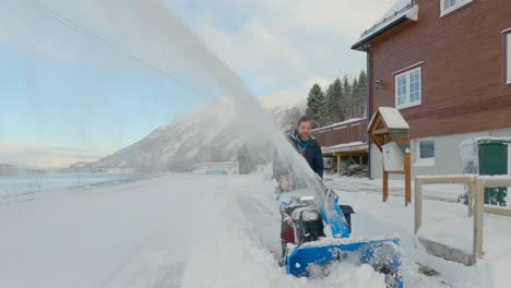 Male-removing-snow-on-a-sunny-day-with-a-snow-blower-after-a-blizzard,-static-shot