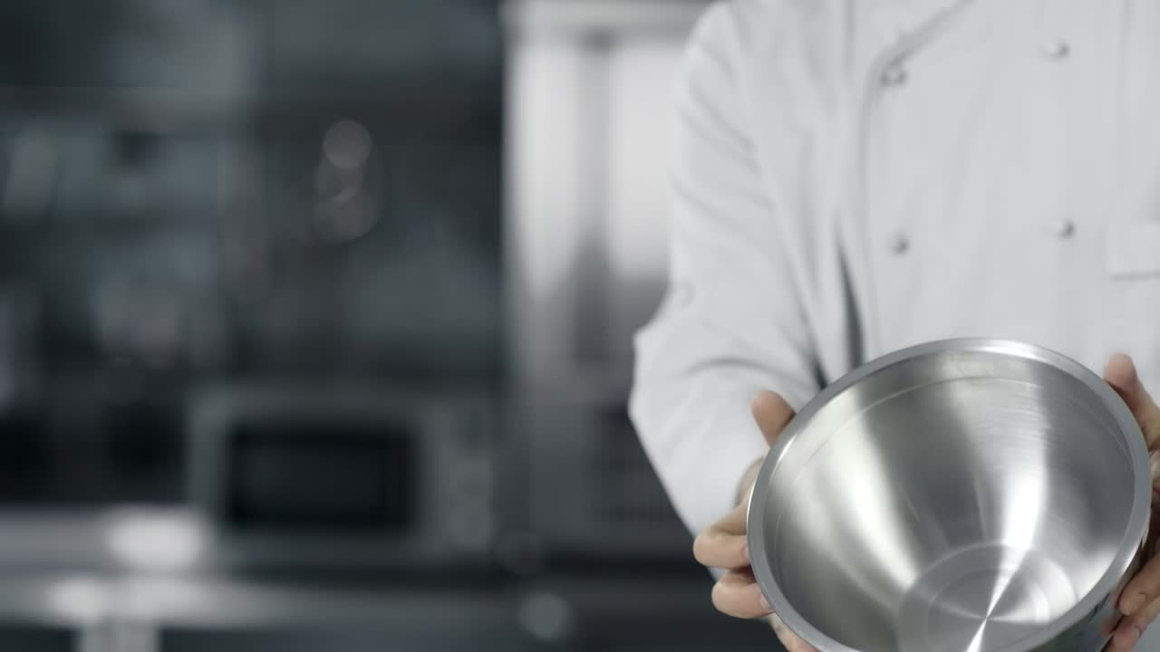 셰프의 손은 느린 움직임으로 강철 그 ⁇ 으로 재미를 느끼고 있습니다. 셰프는 요리를 준비하고 있습니다.