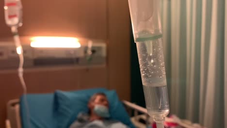 intravenous drip treatment being used to treat a sick man lying on a bed in a hospital