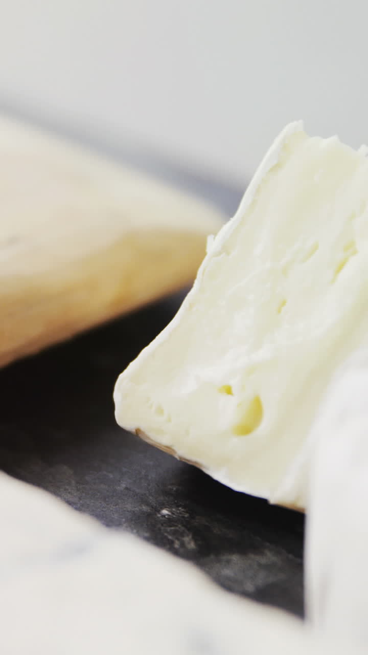 Sliced cheese, bowls of jam and spices on wooden board