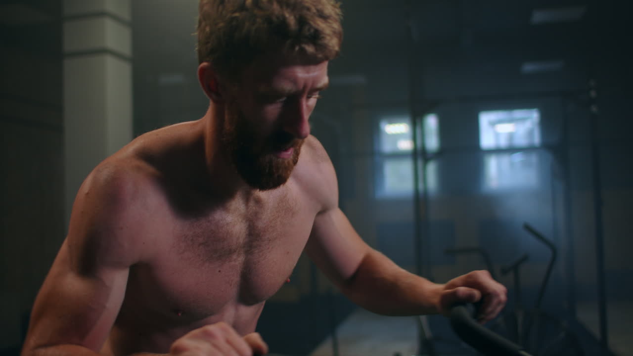 체육관에서 운동 자전거를 사용하는 젊은 남성. 체육관에서 심장 운동을 위해 에어 자전거를 사용하는 피트니스 남성. 장비 노력.