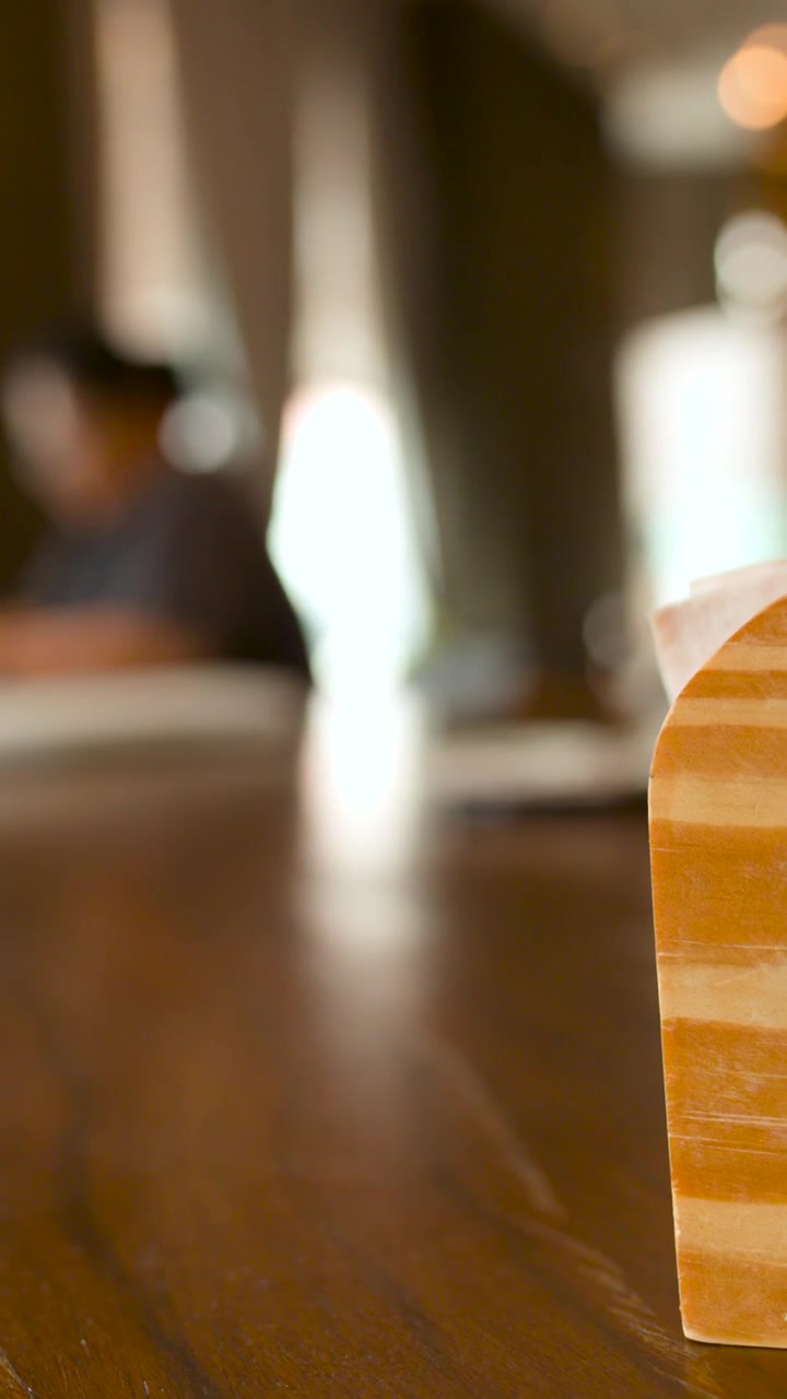 Messa a fuoco selettiva su un portatovaglioli di legno in un ambiente da caffè.
