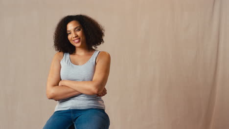 Foto-De-Estudio-De-Una-Mujer-Positiva-Con-Cuerpo-Vestida-Informalmente-Sentada-En-Un-Taburete