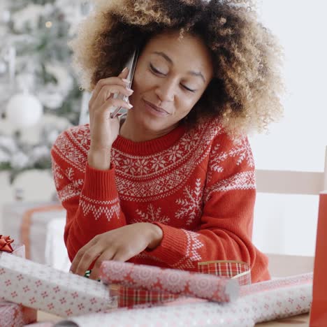 woman chatting on a mobile as she wraps gifts