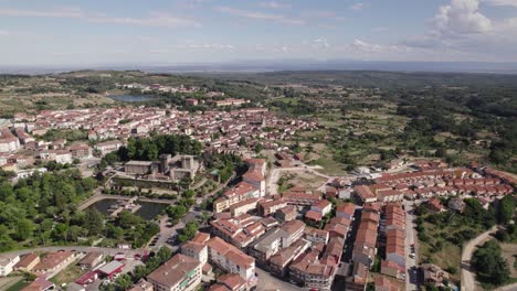 Jarandilla-de-la-Vera-aerial-view-circling-above-colourful-red-tiled-rooftops-and-scenic-Spanish-cityscape-countryside-greenery,-Cáceres