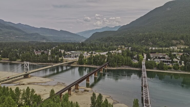 Revelstoke BC Canada Aerial v5 drone flyover Columbia River capturing river crossing bridges, traffics on highway 1 and forested mountain landscape views - Shot with Mavic 3 Pro Cine - July 2023