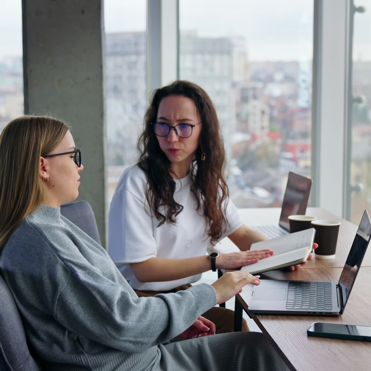 Business ladies discussing work issues in the office. Colleagues look through the images on the laptop screen, looking for new ideas