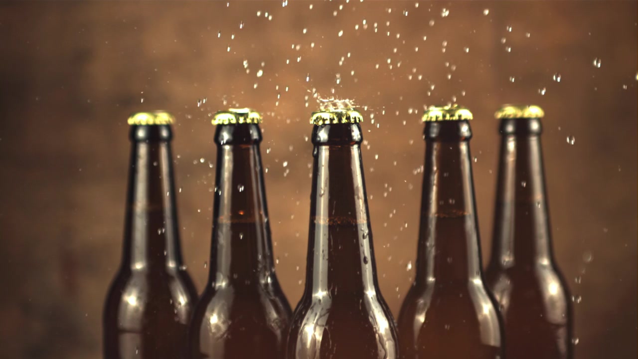 Wassertropfen spritzen in Zeitlupe auf kalte Bierflaschen.