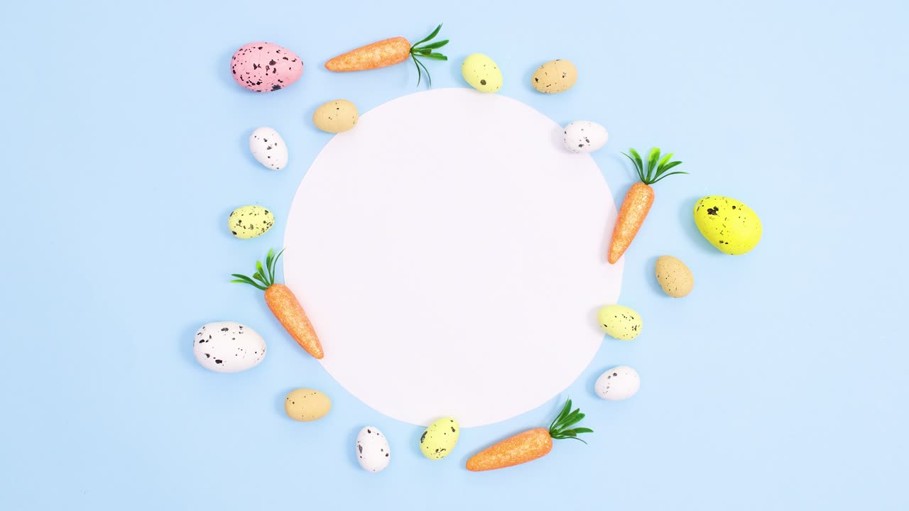 los huevos de pascua y las zanahorias se mueven alrededor de la nota de tarjeta de papel en un fondo azul brillante pastel.