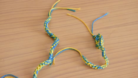 Close-up-view-of-homemade-bracelet-with-Ukraine-flag-colors-blue-and-yellow-on-a-wooden-table