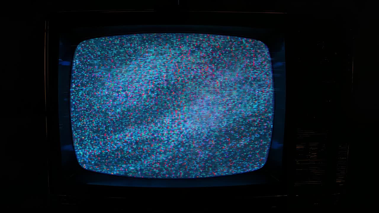 Powering on vintage CRT television screen showing magenta fading to cyan with static in dark room
