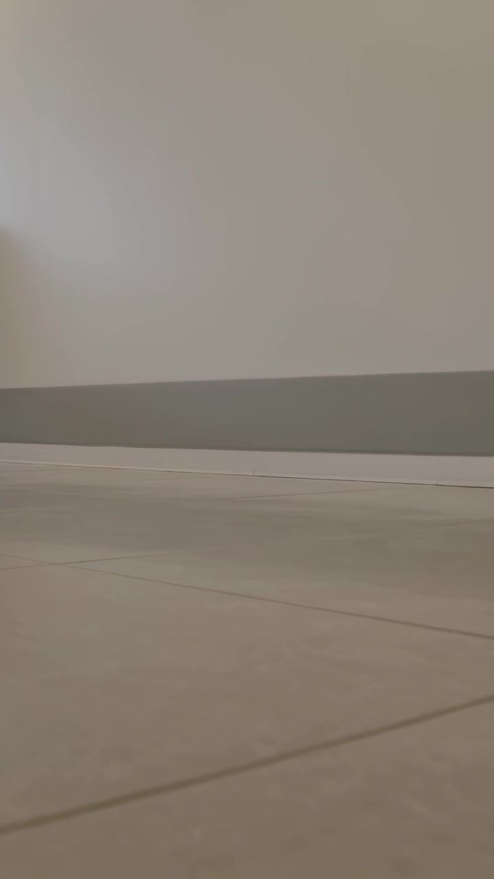 Vertical video: Shifting light moving from window along lower wall and tile floor with baseboard