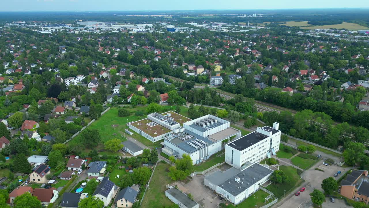 datacenter building with cooling system on the roof, surrounded by residential houses, showcasing urban and industrial integration. Great aerial view flight tilt down drone
