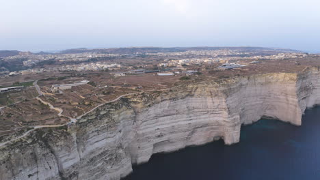 City-on-the-edge-of-coastal-cliffs-of-Gozo-island,Malta,aerial-shot