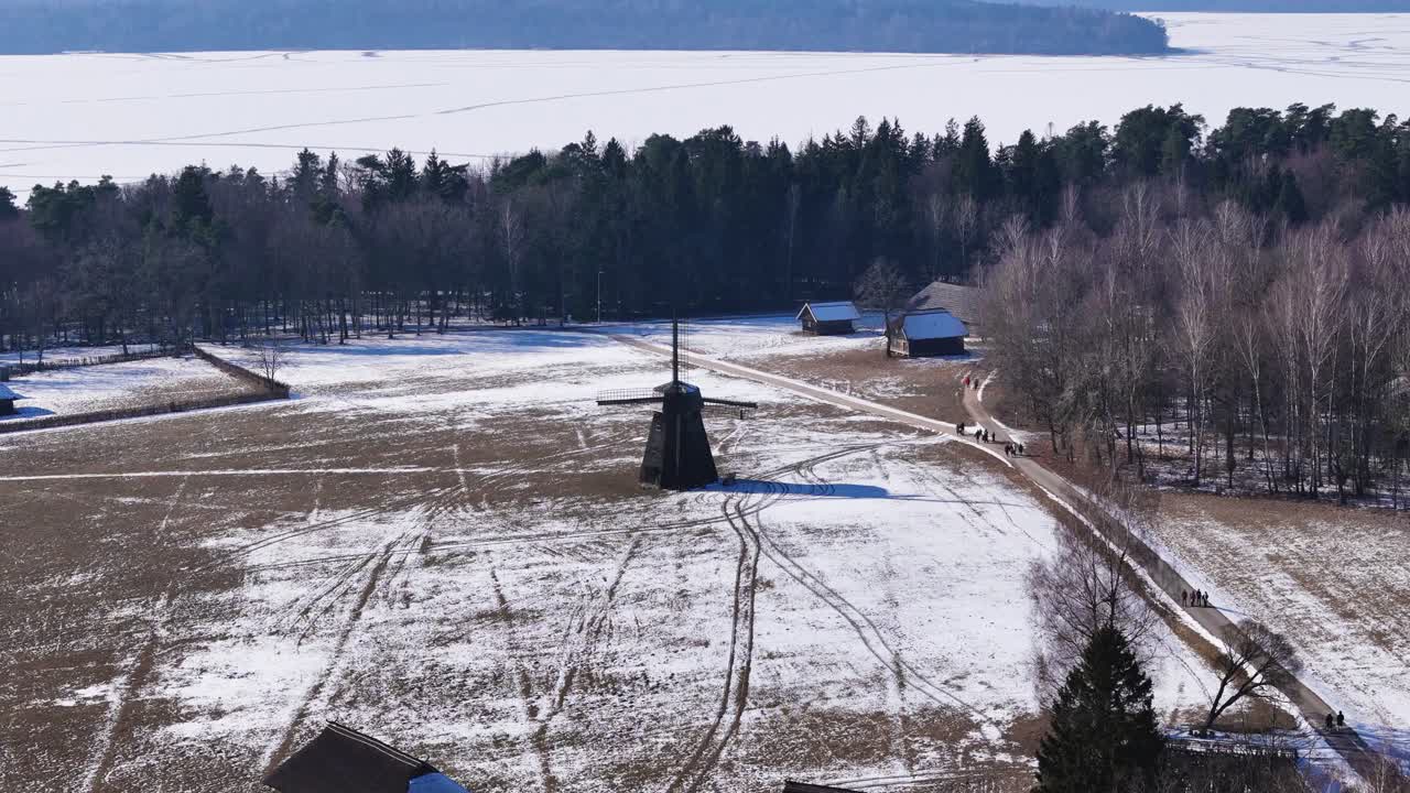 Old wooden millhouse near village in winter, aerial view