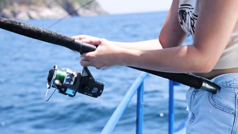 una persona maneja hábilmente una caña de pescar en un barco en phuket, tailandia, bajo la luz del día, capturando un momento de pesca sereno