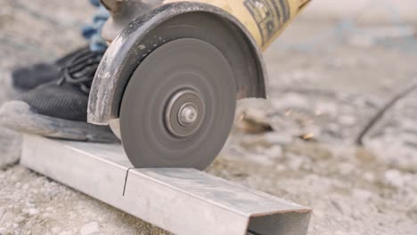 worker cutting metal with electric circular saw outdoors on construction site,slow motion