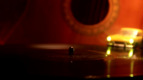 slider shot. disco de vinilo vintage tocando en el reproductor y la guitarra acústica en el fondo con humo de naranja de fuego. concepto de crimen o blues con instalación de automóvil de juguete. enfoque selectivo