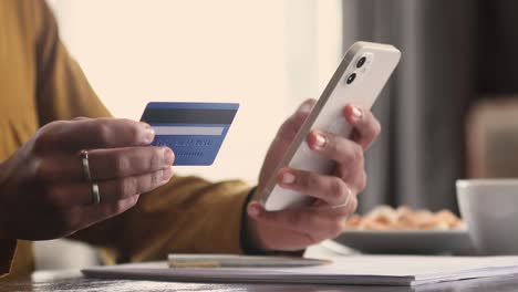 closeup female hands holds cellphone and card buy goods online