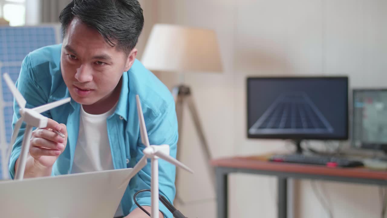 아시아 남녀가 풍력 터빈과 노트북 컴퓨터로 작업에 대해 논의합니다.