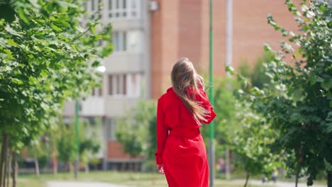 gorgeous woman in red dress in the city. young woman with long hair talking on the phone on the city background. sllow motion.