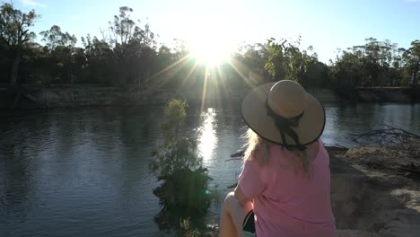 blonde woman sitting on rivers edge sunset australian fauna camping