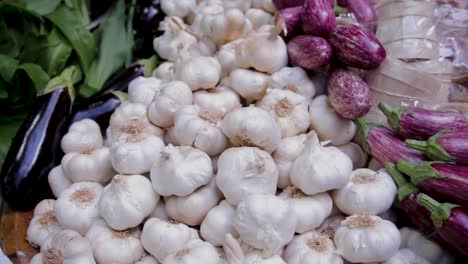 garlic bulbs and eggplants in the fresh produce section of the grocery store